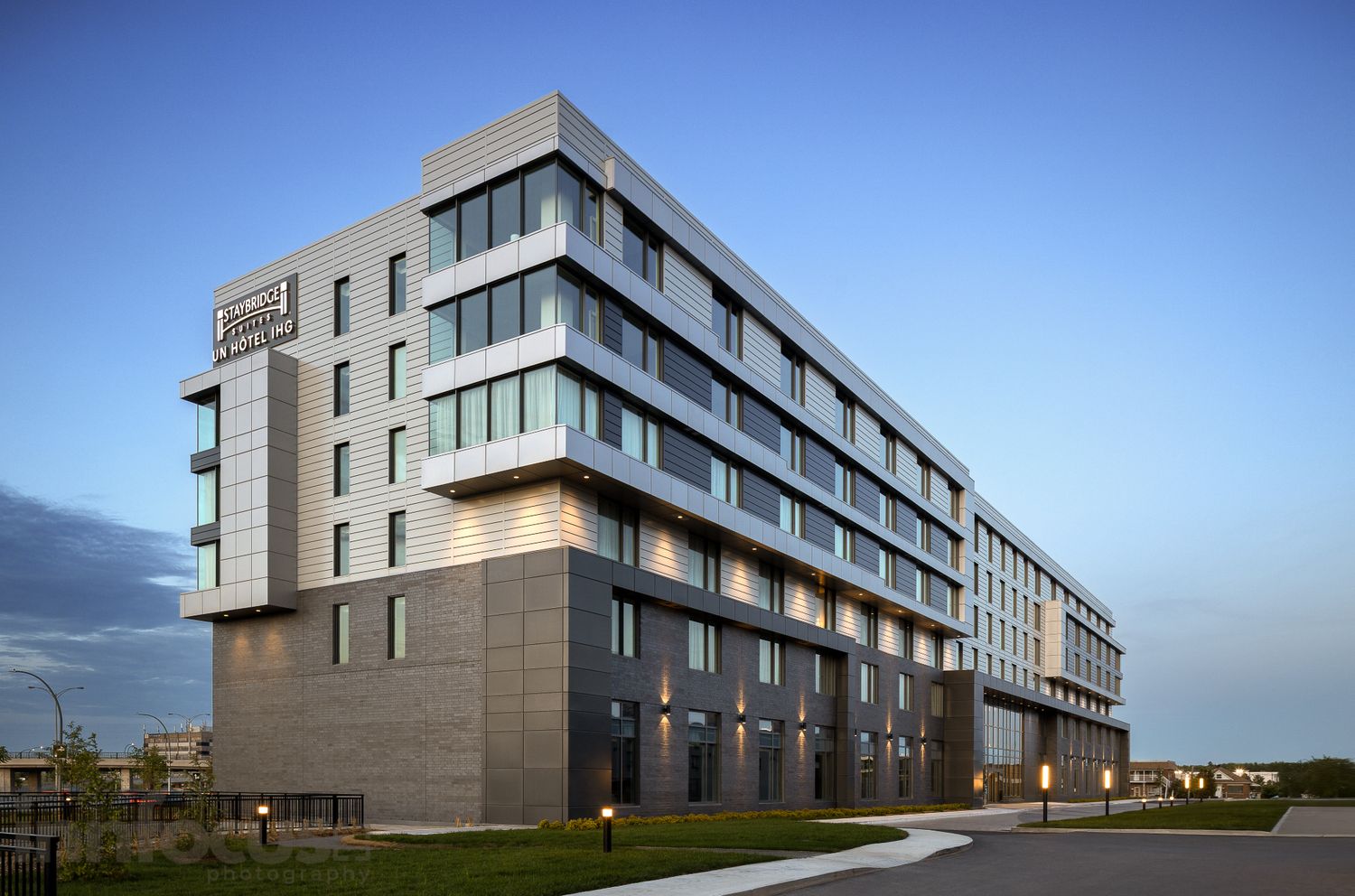 Modern Staybridge Suites hotel exterior featuring contemporary architecture with gray facade and illuminated windows at dusk.