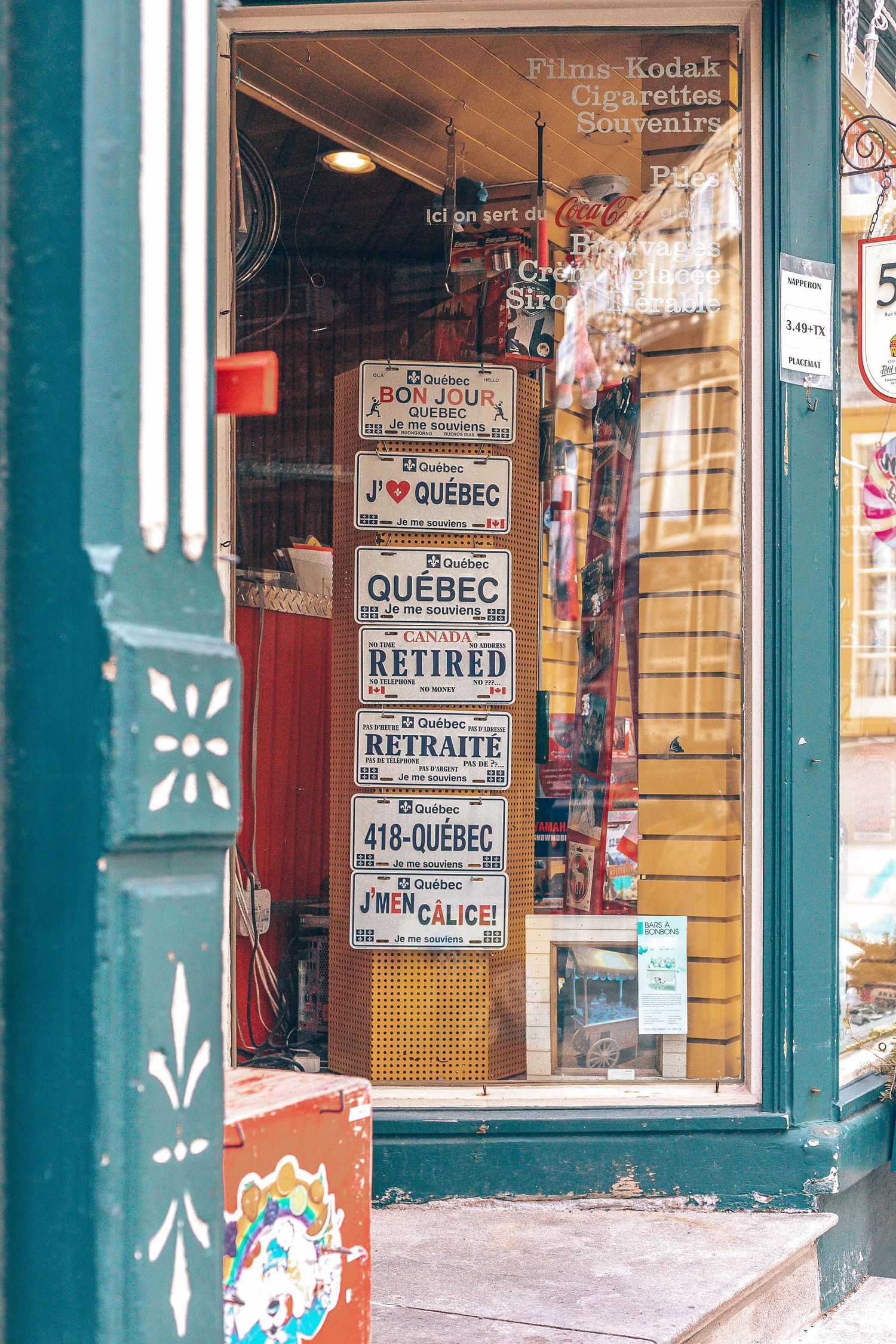 Store window display showcasing Quebec-themed signs and souvenirs in a charming shop front.