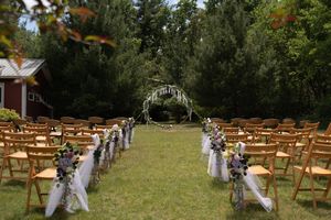 Elegant outdoor wedding ceremony setup with wooden chairs, floral decorations, and a floral arch.