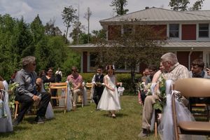 Flower girl walking down the aisle at an outdoor backyard wedding ceremony.