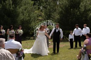 Smiling bride and groom walk back down the aisle after ceremony with wedding party and guests applauding.