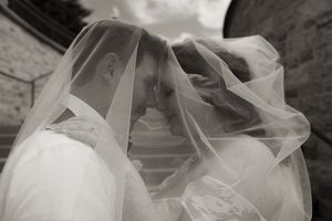 Black and white photo of bride and groom sharing intimate moment under wedding veil.
