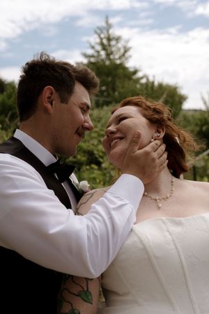 Bride and groom share a tender moment, groom gently cupping brides face at outdoor wedding.