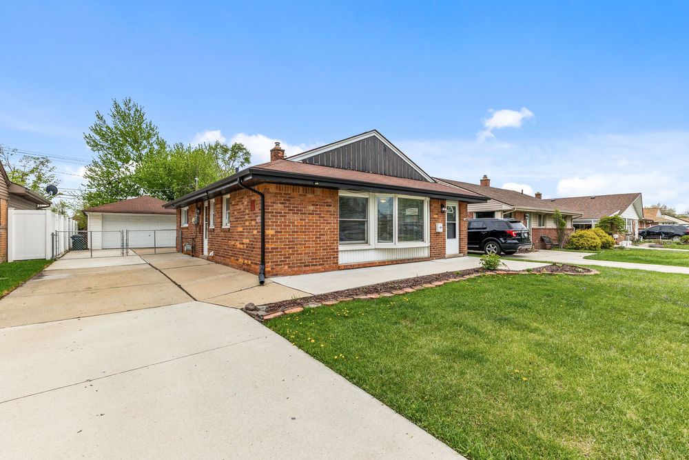 Brick ranch-style home with lush green lawn, attached garage, and classic Midwest suburban curb appeal on a sunny day.