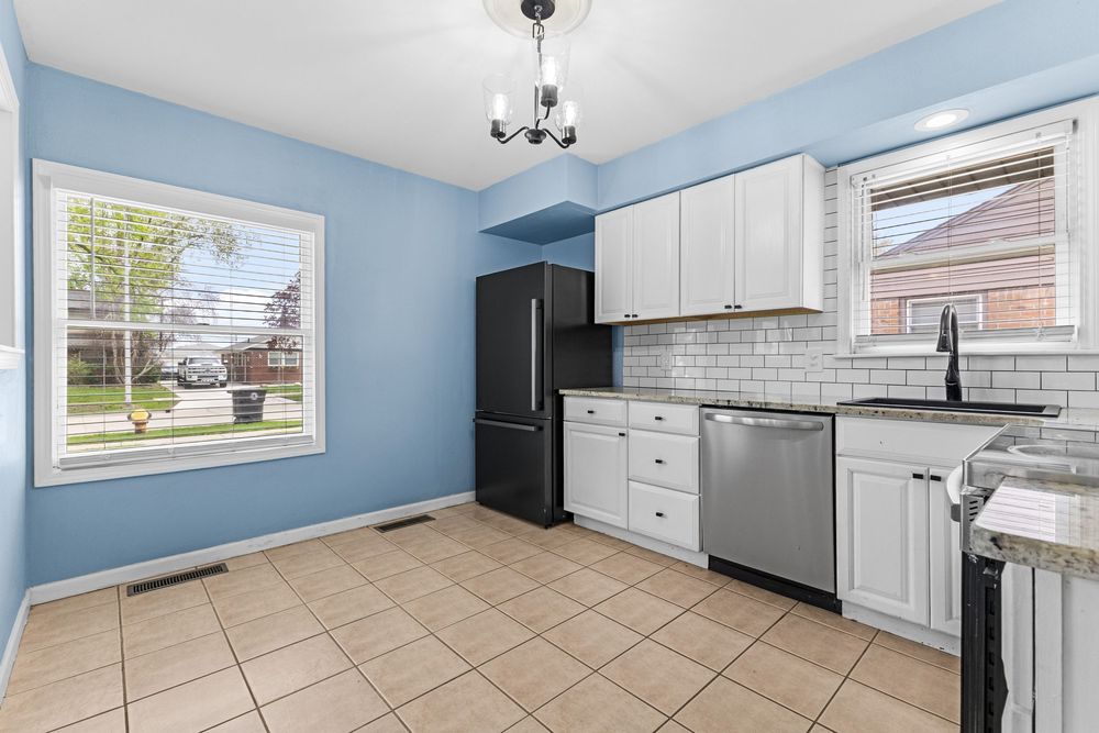 Modern kitchen with white cabinets, subway tile backsplash, stainless steel appliances, and light tile flooring.