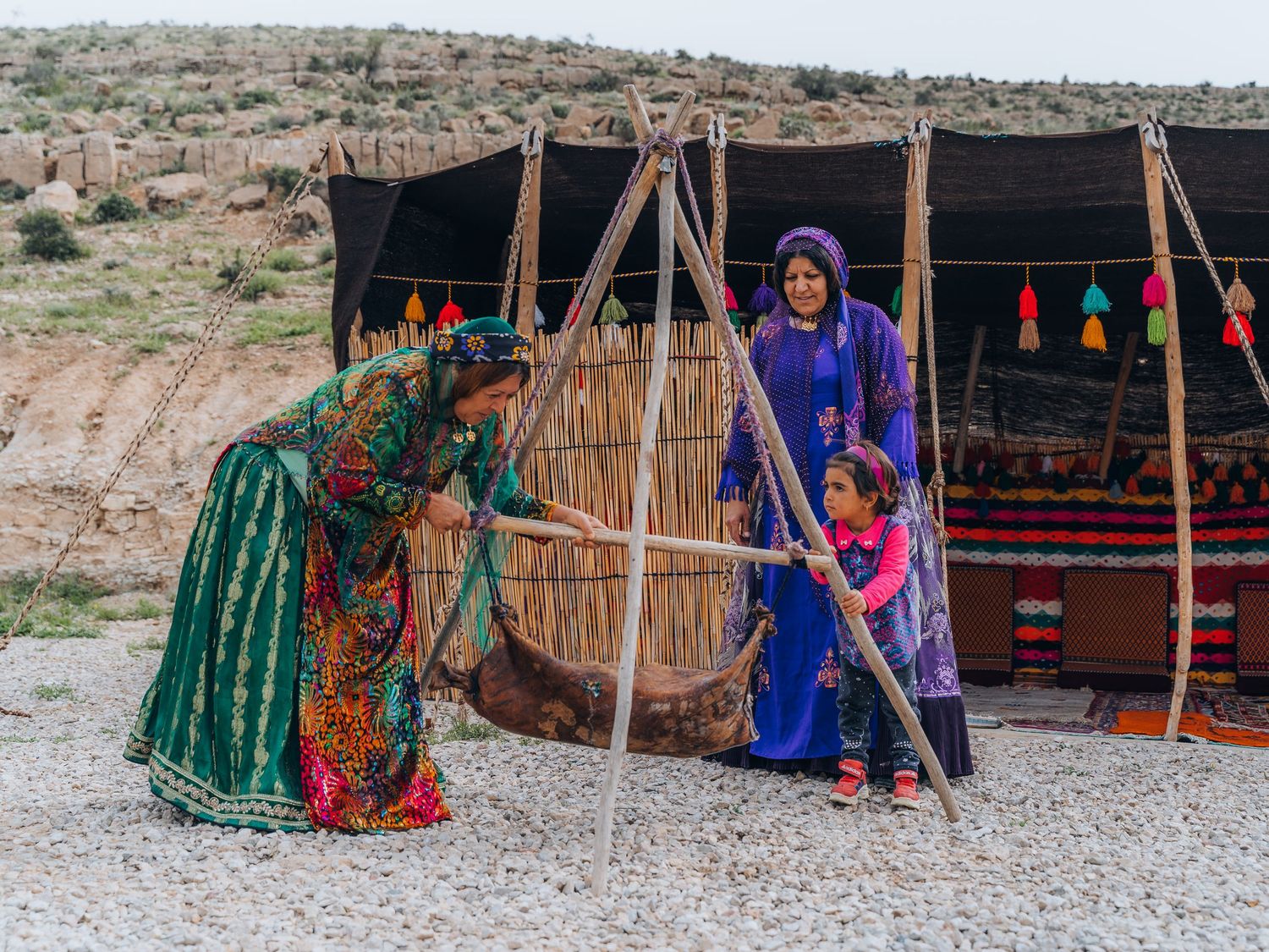 Qashqai nomad women and a girl with a traditional leather butter churn outside their tent, Firuzabad, Fars, Iran.
