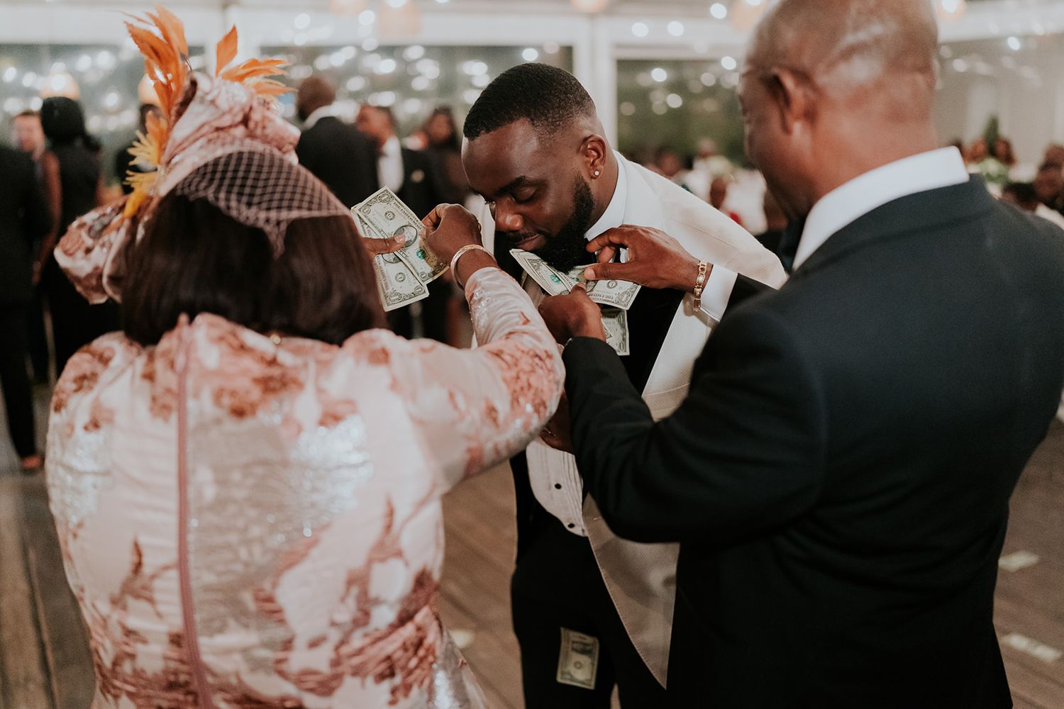 Wedding guests helping adjust formal attire during an outdoor celebration.