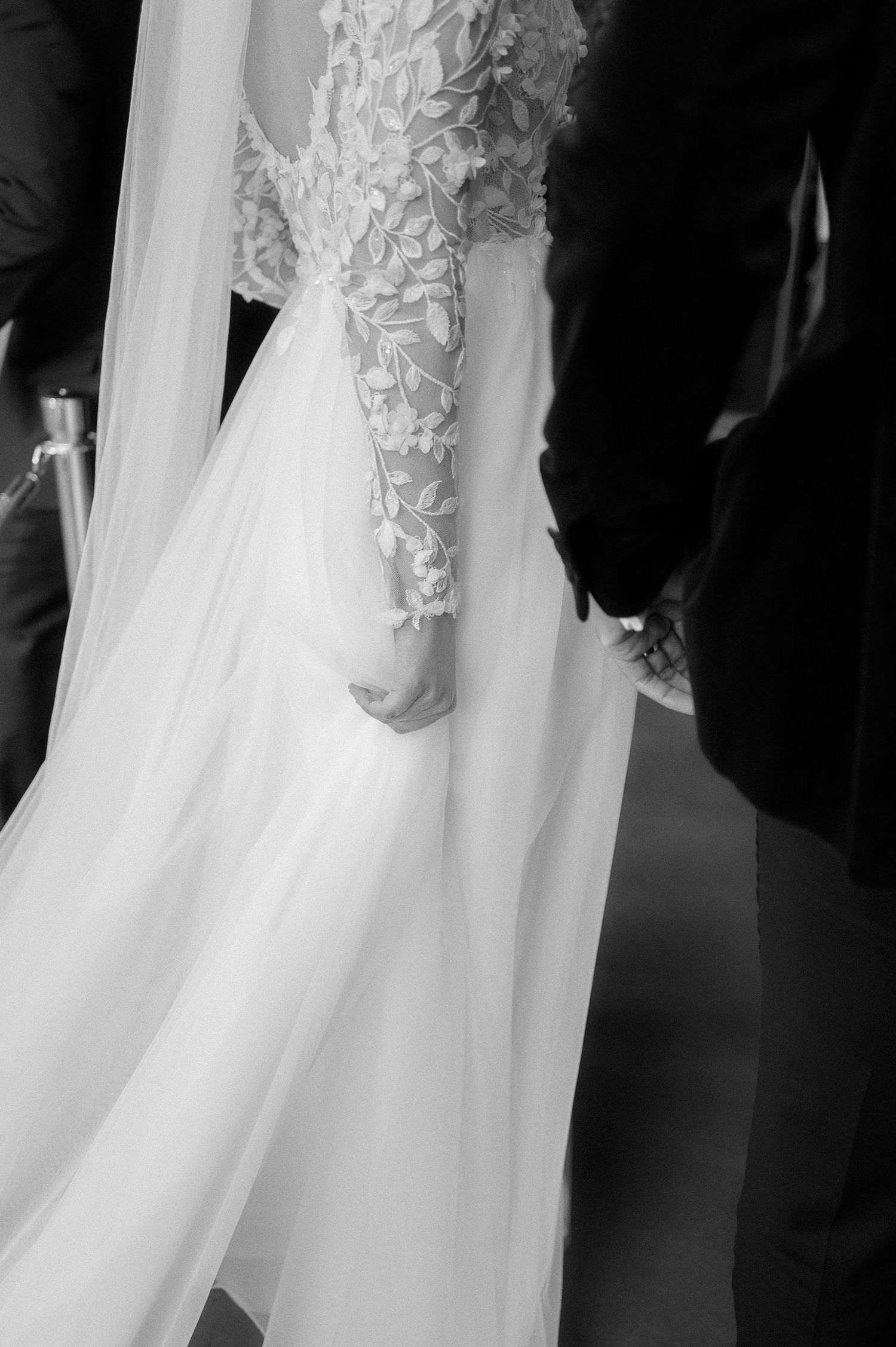 Black and white wedding photo of couple embracing and laughing in elegant church hall with gothic windows.