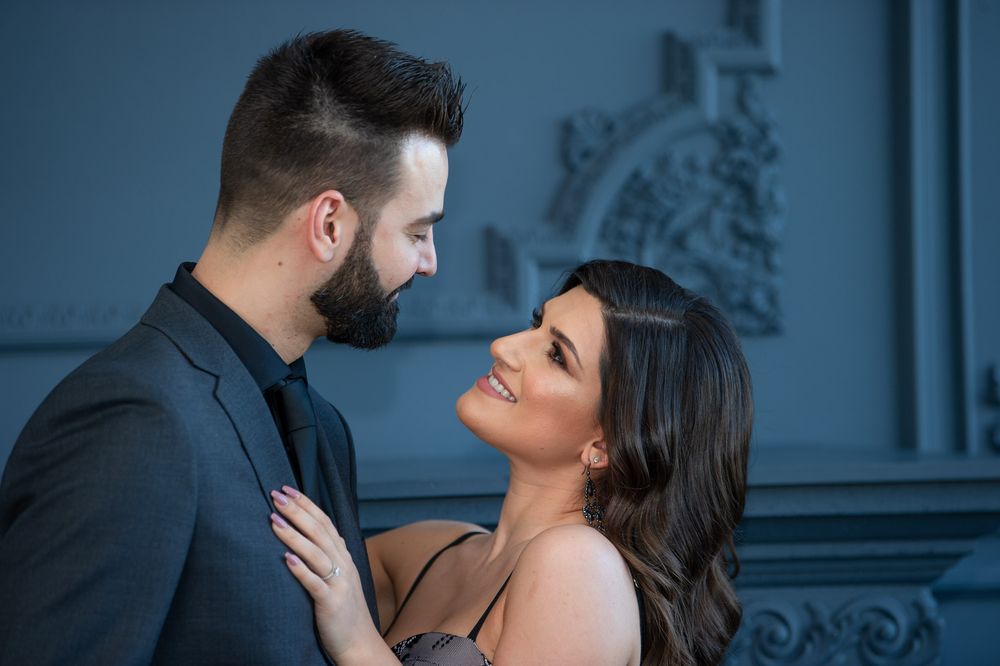 A stylish couple gazes lovingly at each other in a softly lit blue-gray room.