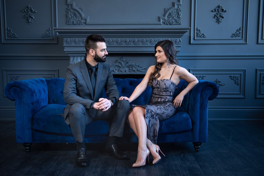 Couple sharing an intimate conversation on blue velvet sofa in sophisticated gray paneled room.