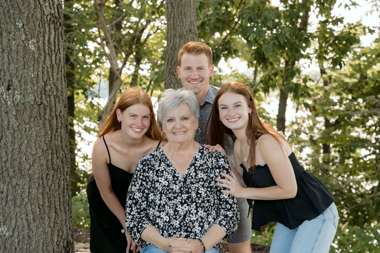 three teenagers snuggle around grandma for summer cabin portraits on lake wissota in chippewa falls, wi