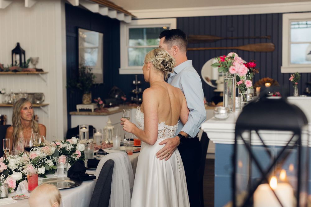 Bride and groom share a romantic moment at their wedding reception, surrounded by floral arrangements and elegant table settings.