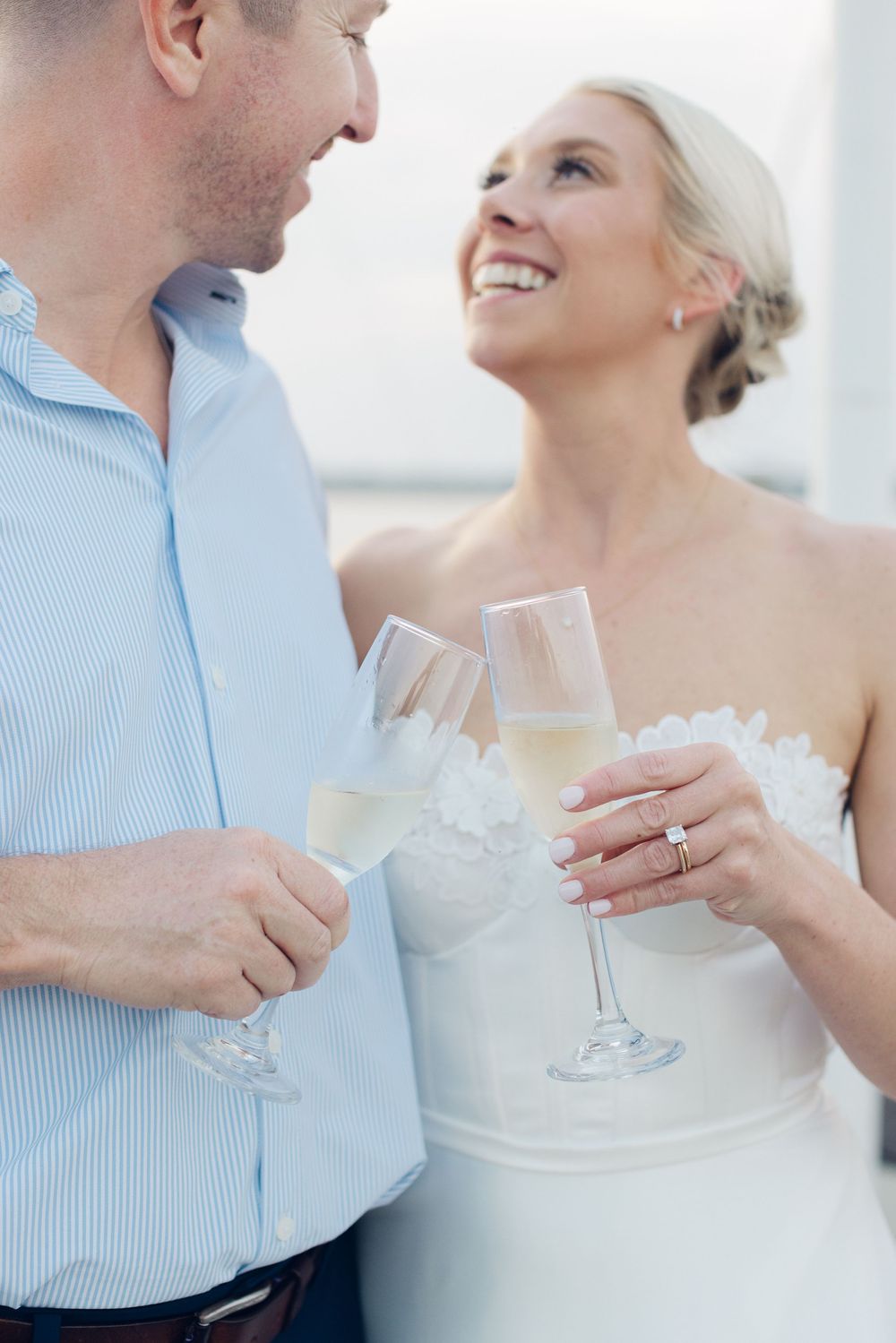 Happy bride and groom toasting with champagne glasses, smiling at each other on their wedding day.