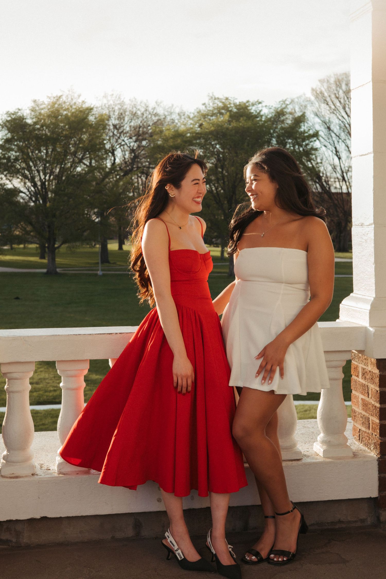 Two women photographed outdoors with warm light, colorful dresses and natural smiles for a fun Brookings SD portrait session.