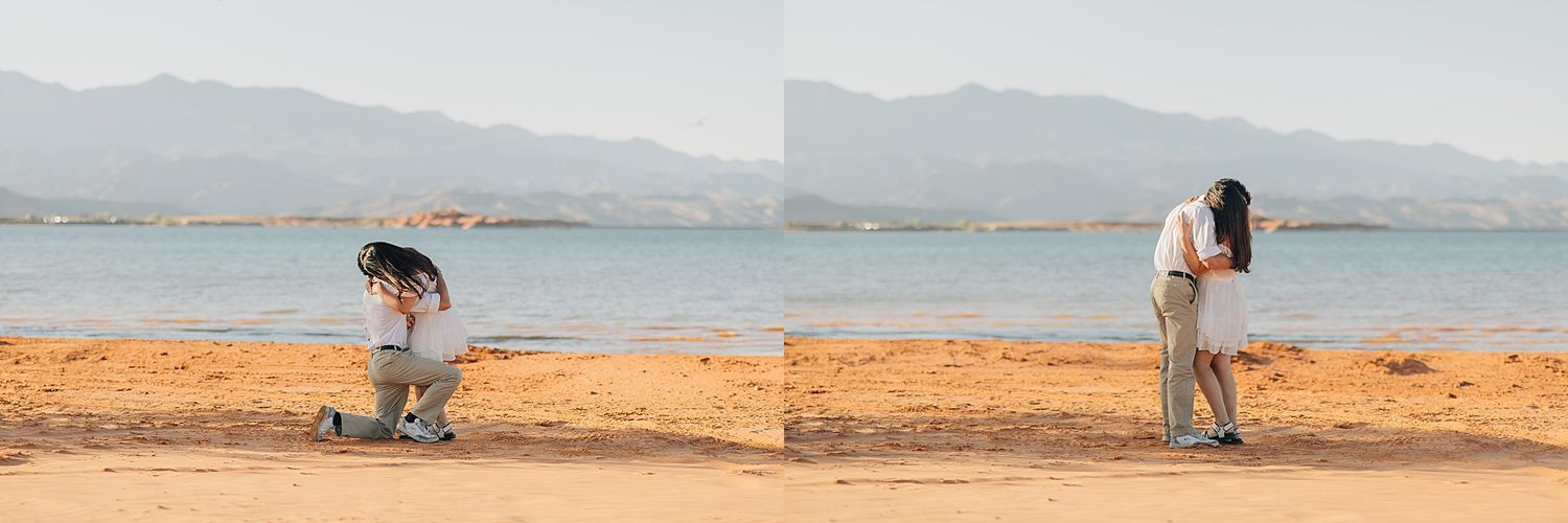 Couple sharing a romantic kiss on a sandy beach with mountains and a lake in the background during a marriage proposal.