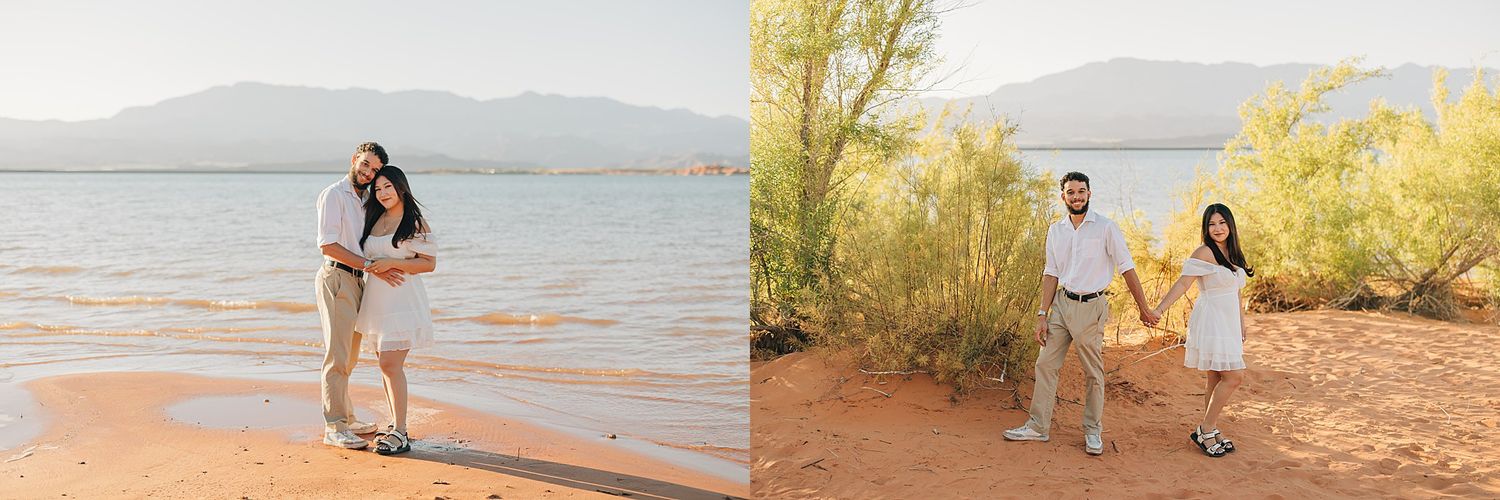 Couple poses on red sandy shore near lake with mountains, wearing coordinating white and khaki outfits.