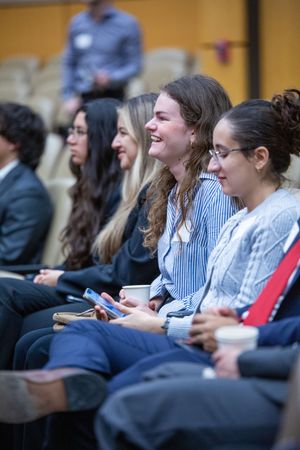 Students smiling and laughing while seated in an auditorium during a professional conference or academic event.