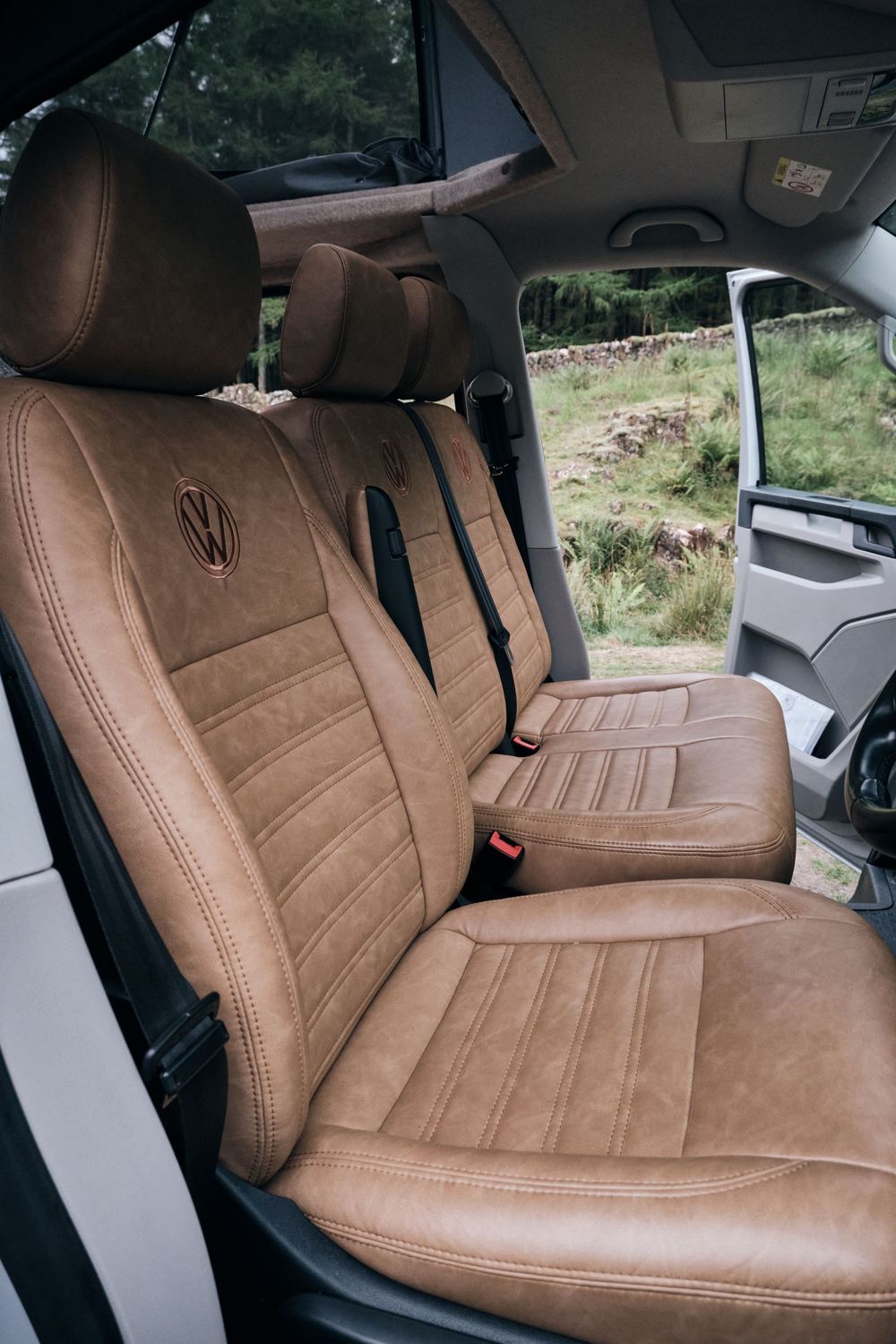 Luxurious tan leather VW Volkswagen car seats with embroidered logo and detailed stitching inside a vehicle.