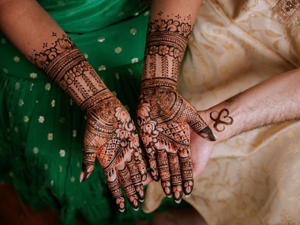 Intricate henna mehndi designs on bride's hands and arms at an Indian wedding ceremony.