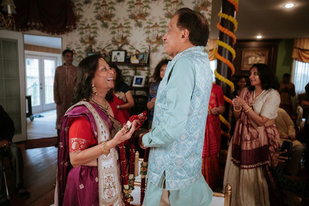 Two guests in traditional Indian attire laugh together during a festive indoor celebration.