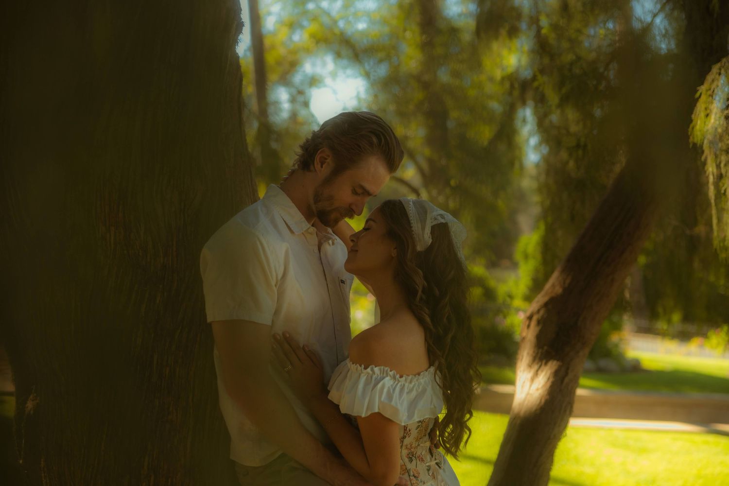 Romantic couple sharing an intimate moment leaning against a tree on the grounds of the Kimberly Crest House wedding venue.