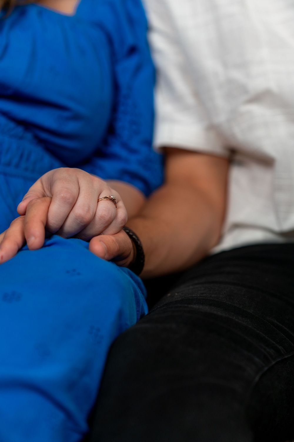 Detailed lifestyle shot focusing on a man and woman's interlocking hands, highlighting a close personal connection in minimalist fashion.