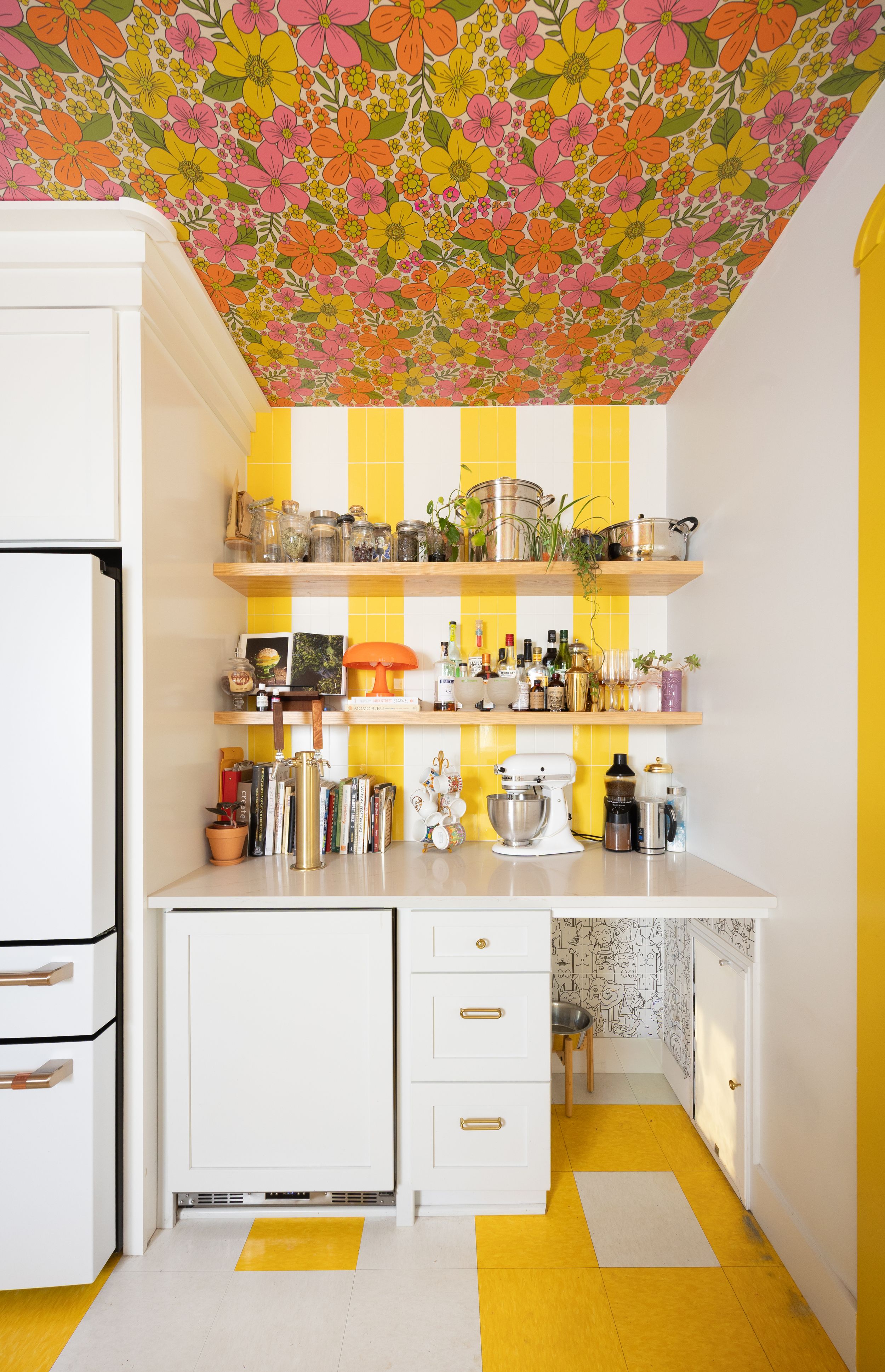 Bright kitchen bar area with floral ceiling, yellow striped backsplash, and open shelving.