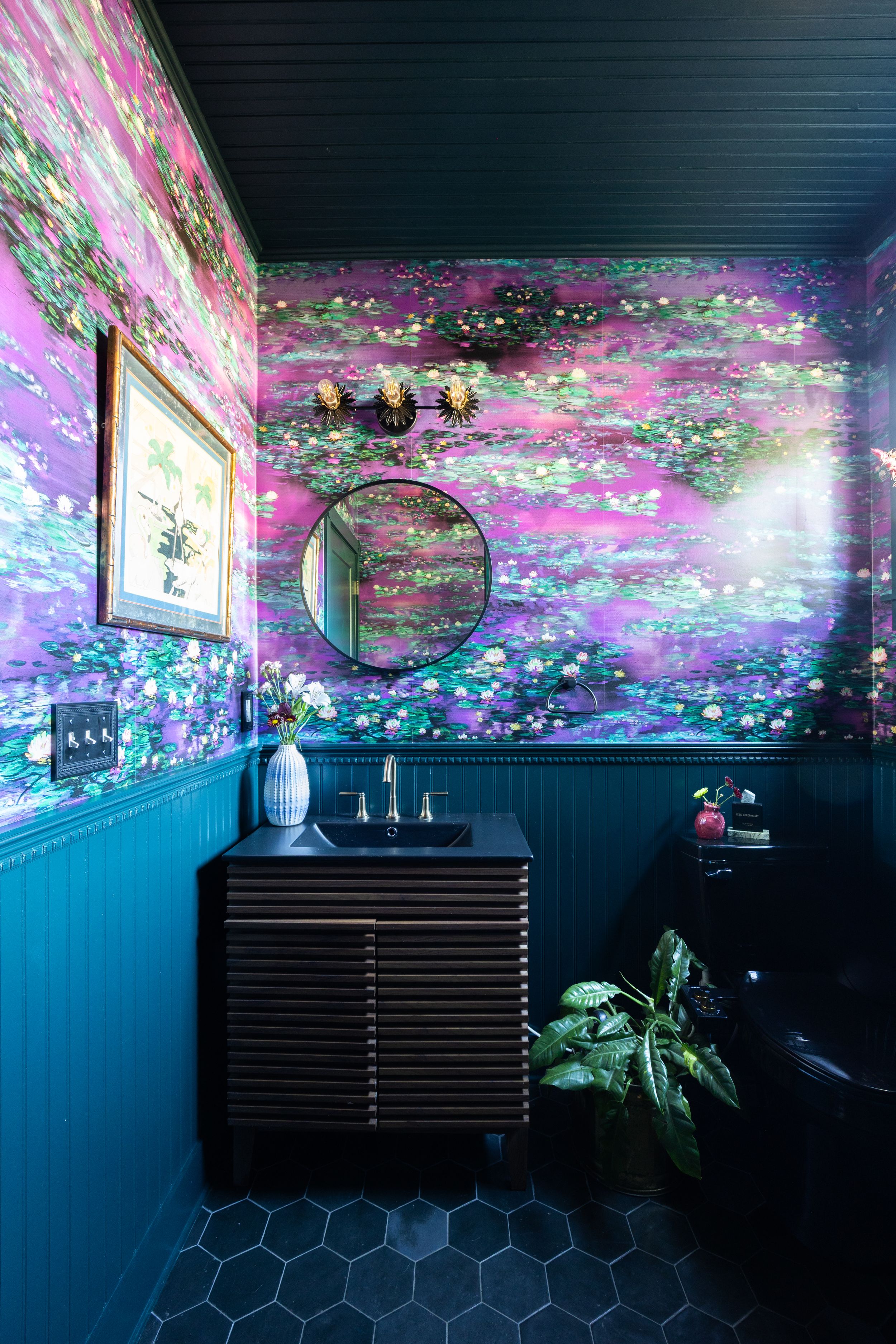 Bold powder room with purple floral wallpaper, dark teal wainscoting, and hexagon tile floors.