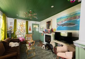 Cozy living room with dark green ceiling, whale art, fireplace, dogs, and Christmas decorations.