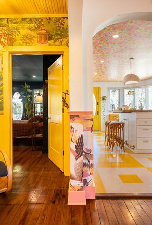 Eclectic home interior with yellow doors, tropical wallpaper, and checkered kitchen floor.