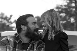Black and white photo of a bearded man and young girl sharing a joyful moment outdoors.