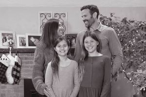 Black and white family Christmas portrait with two girls near a decorated holiday tree.