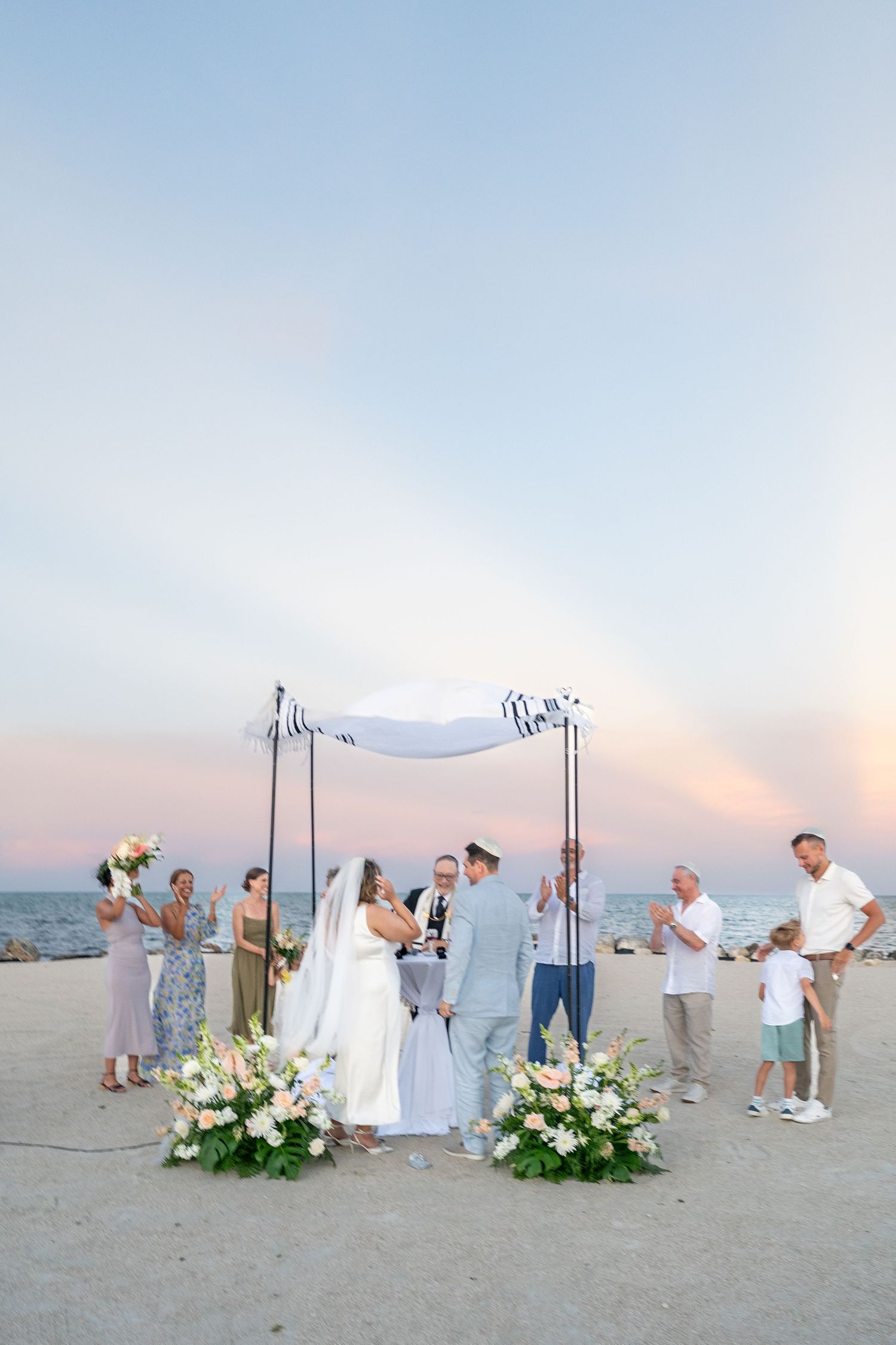 Bride and groom sharing a romantic kiss under a flowing white veil, bride holding a bouquet.