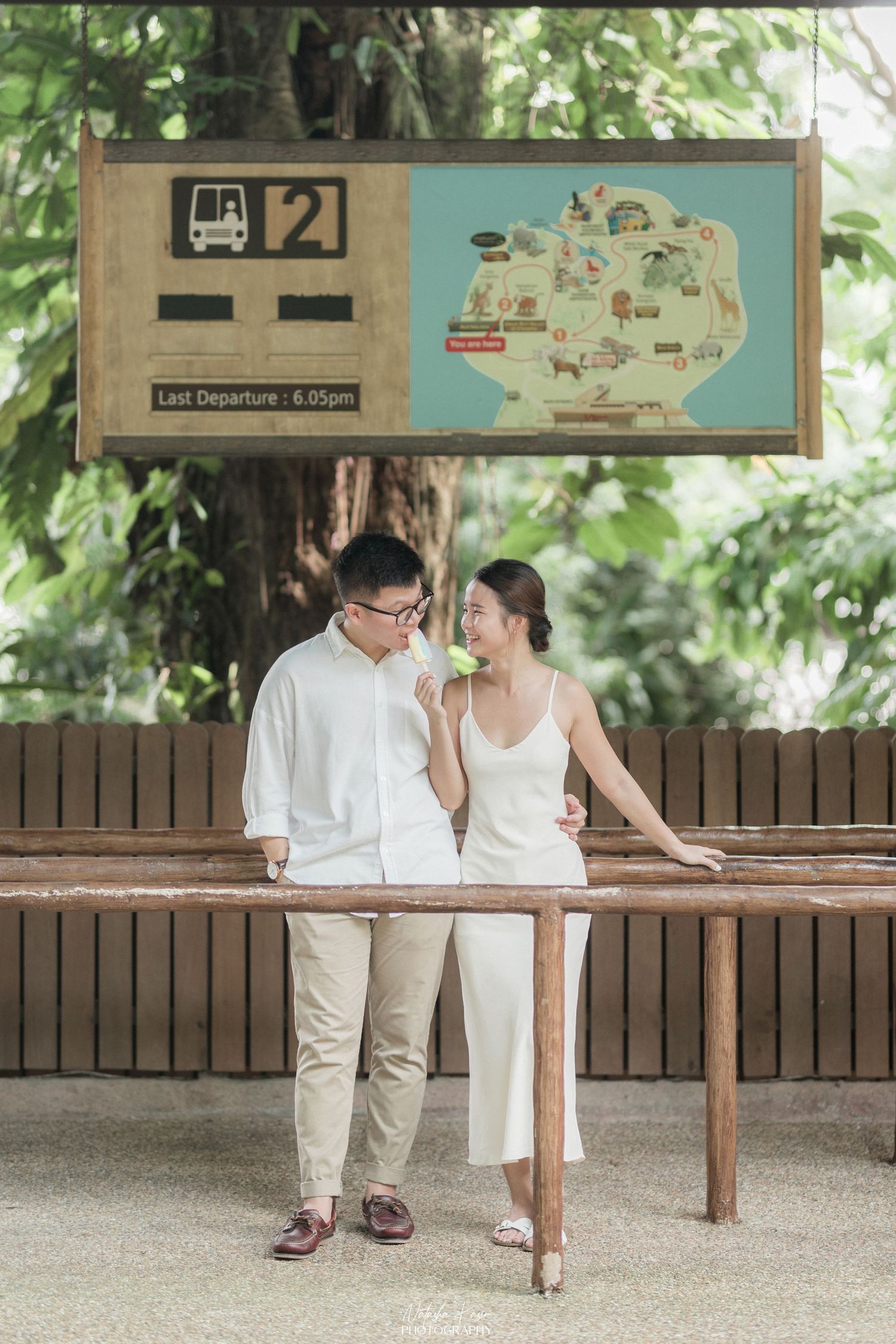 A couple in white attire dancing gracefully in a garden setting with lush greenery in the background.