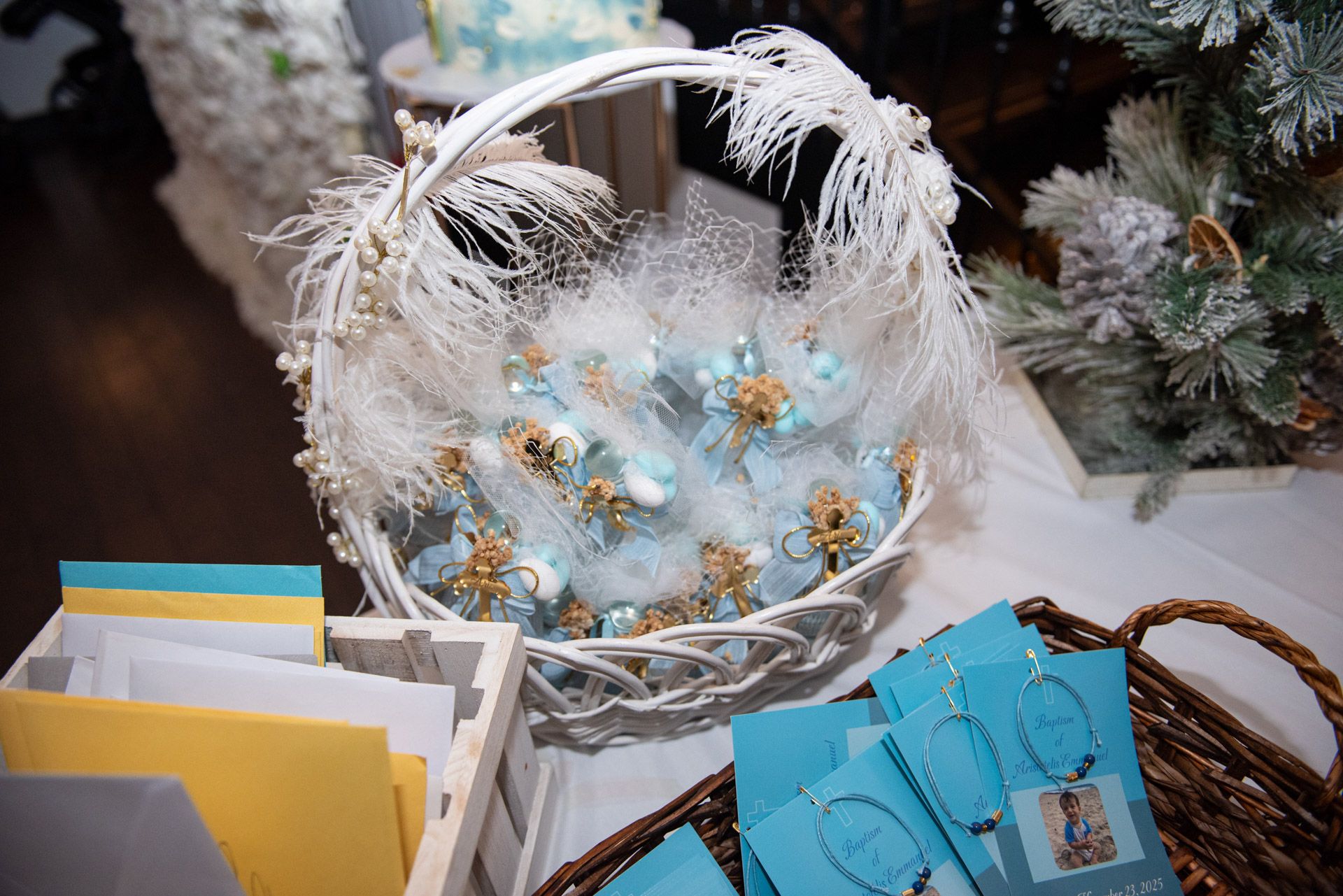 A white wicker basket filled with light blue baptism favor decorations with feather trim.