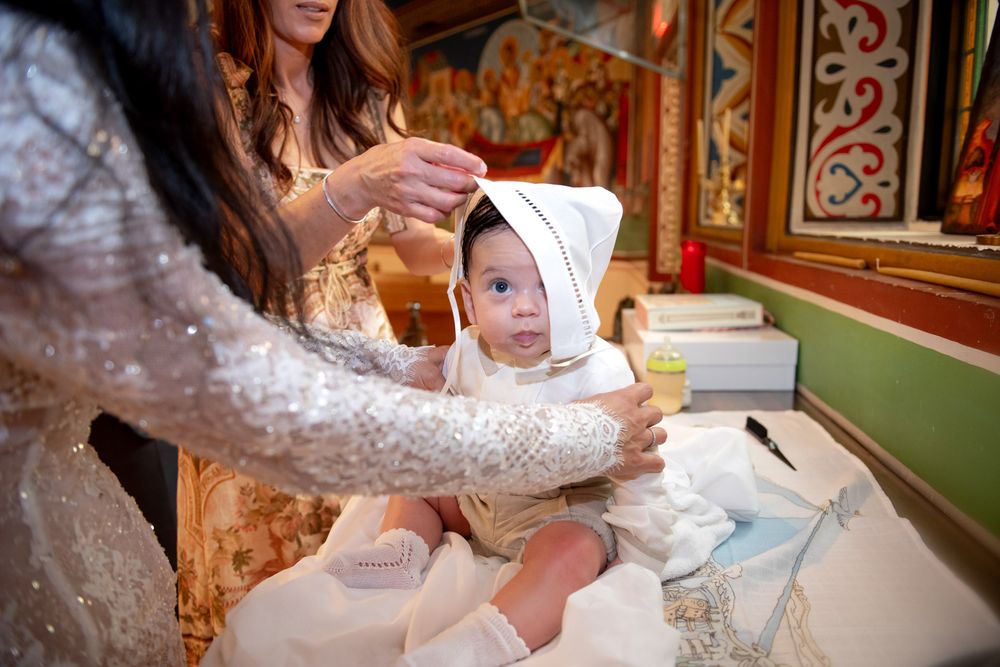 Baby in white baptism gown being dressed after Orthodox christening ceremony.