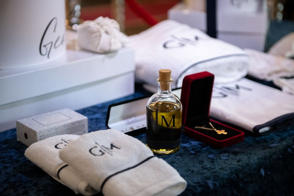 Baptism gift set with monogrammed white towels, olive oil bottle, gold cross necklace, and keepsakes.