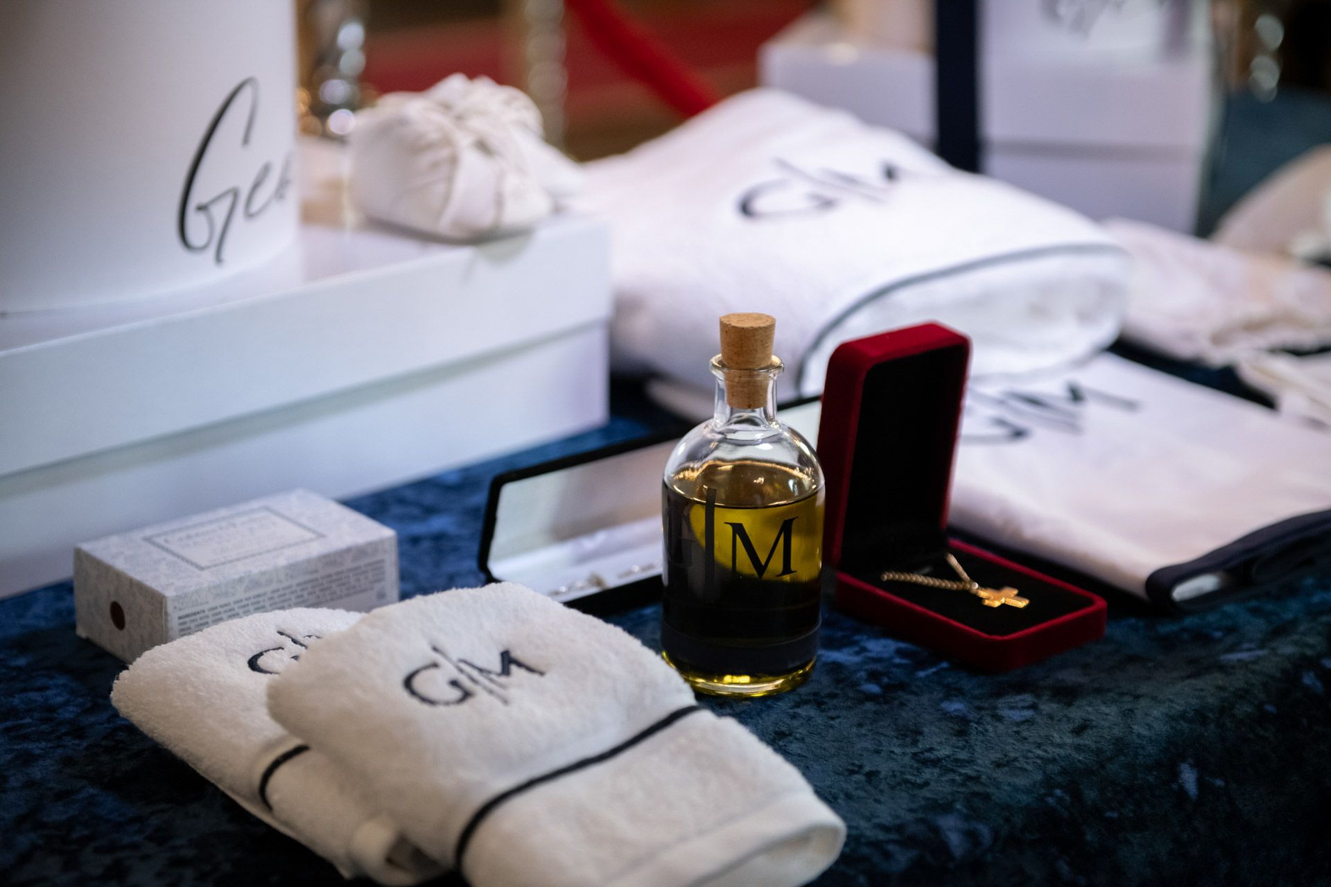 Baptism gift set with monogrammed white towels, olive oil bottle, gold cross necklace, and keepsakes.