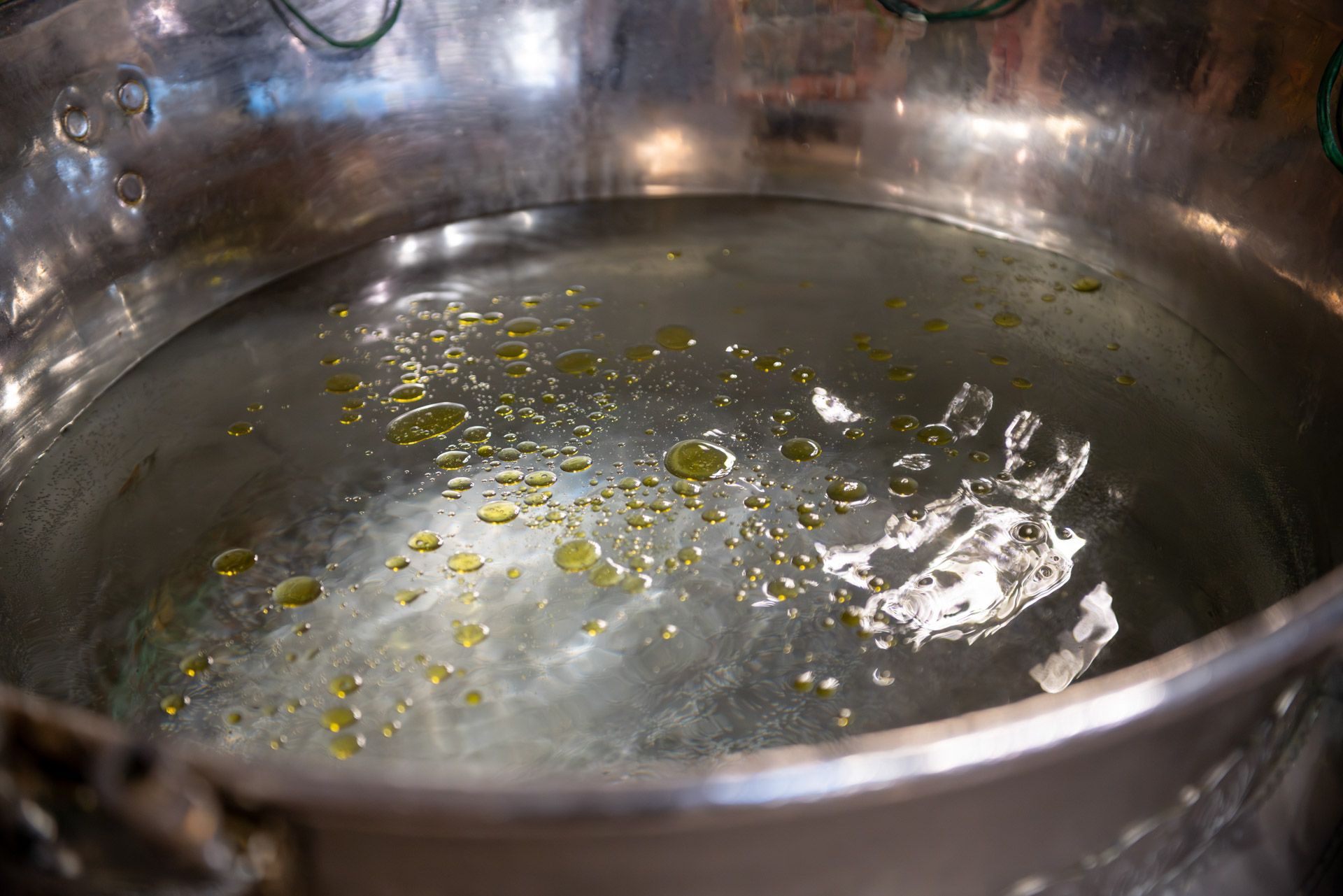 A golden metal basin filled with water and olive oil used in an Orthodox baptism ceremony.