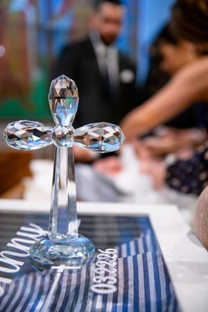 A crystal glass cross decoration sits on a blue striped baptism table centerpiece.