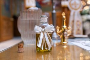 A decorative glass bottle of olive oil with a white bow, used in Orthodox Christian baptism rituals.