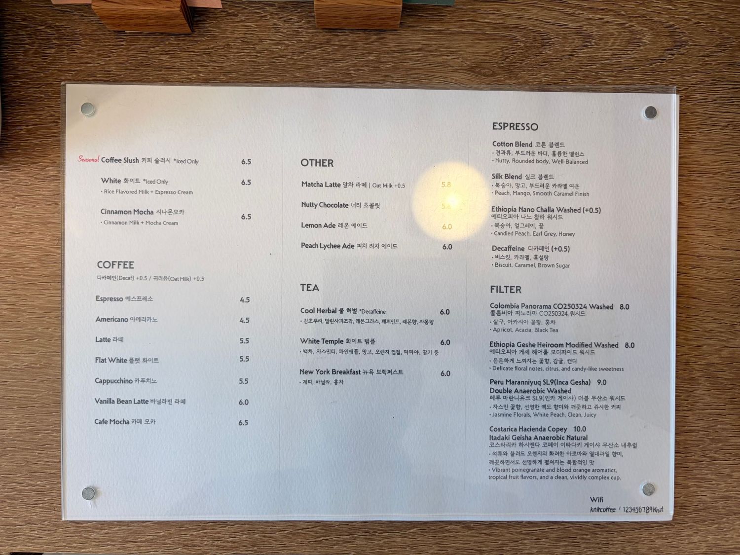 A laminated cafe menu board displaying espresso, coffee, tea, filter, and other drink options with prices.
