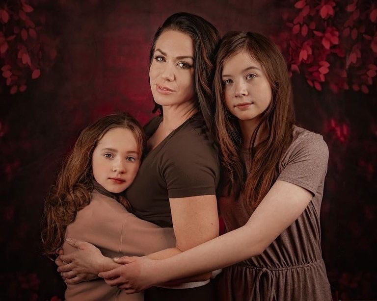 Family portrait series showing tender embraces against a moody dark background.
