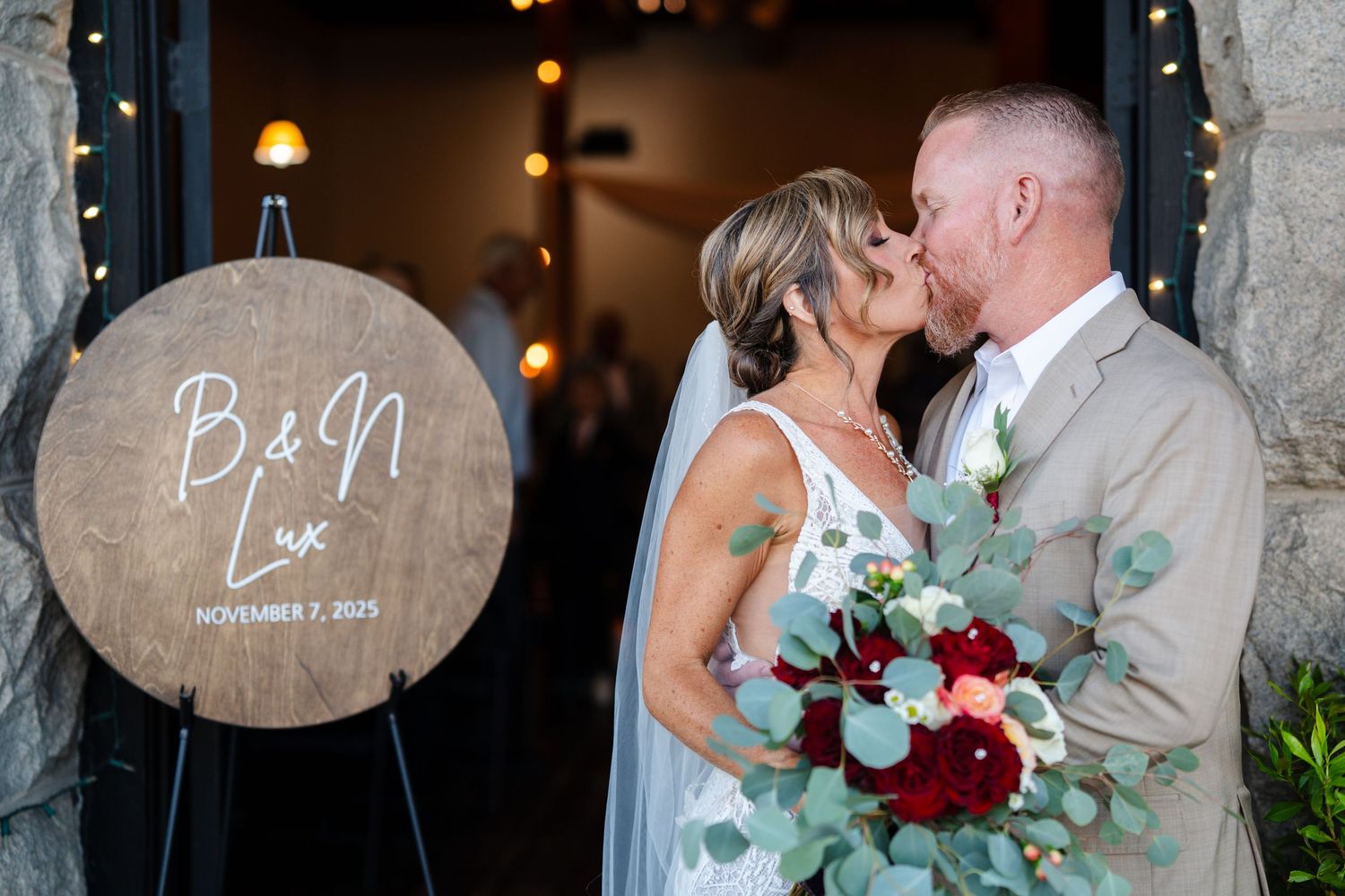 Romantic wedding couple embraces in an elegant venue with soft lighting and floral decorations.