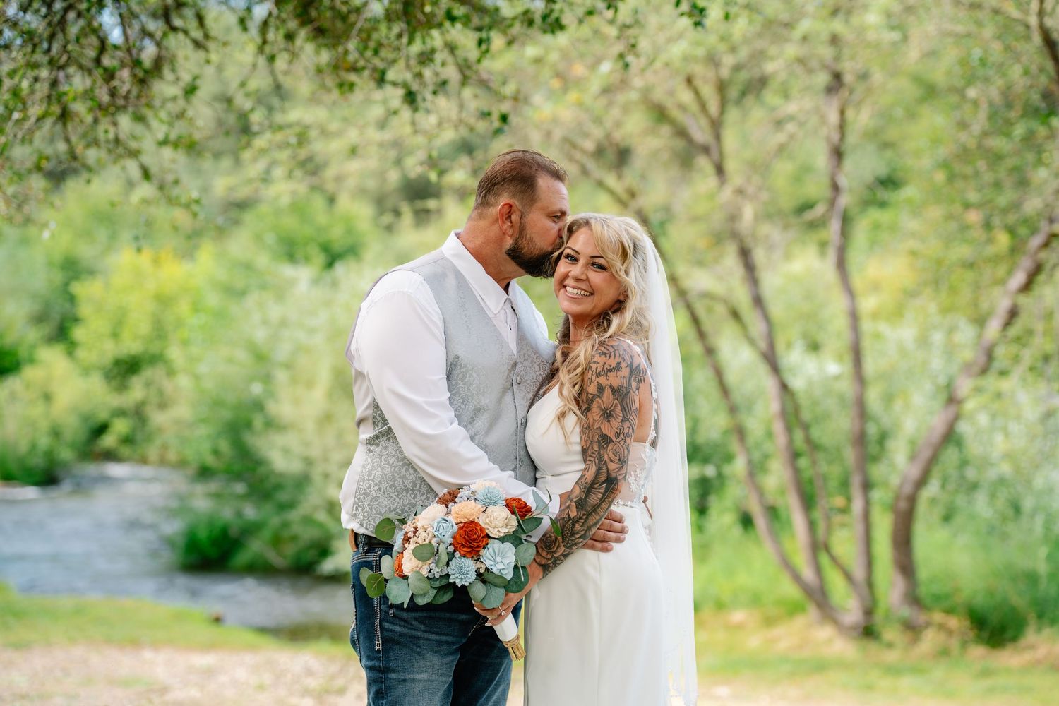 Romantic wedding couple embraces in an elegant venue with soft lighting and floral decorations.