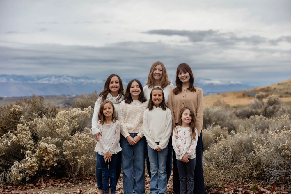 Casual outdoor family photo shoot with desert mountains and brush in the background.