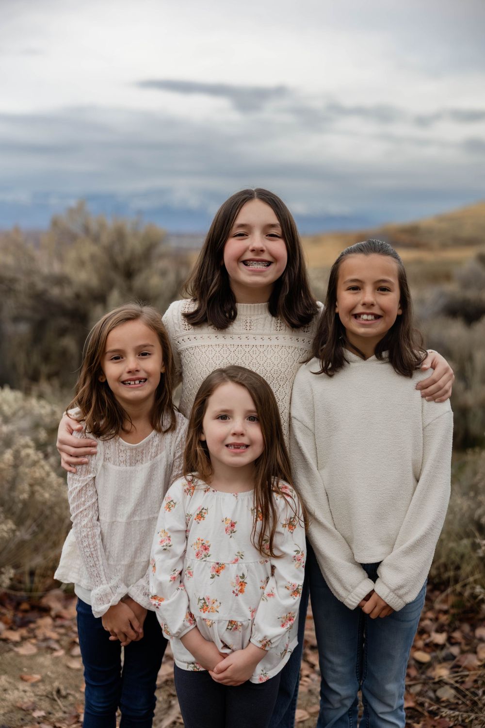 Group portrait of children in light-colored sweaters against a desert backdrop.