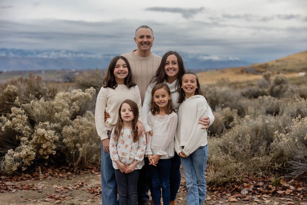 Family members pose together in coordinated outfits against a desert mountain landscape.