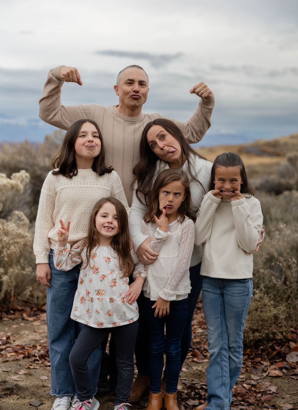 Playful family photo with everyone making silly faces outdoors in the desert.
