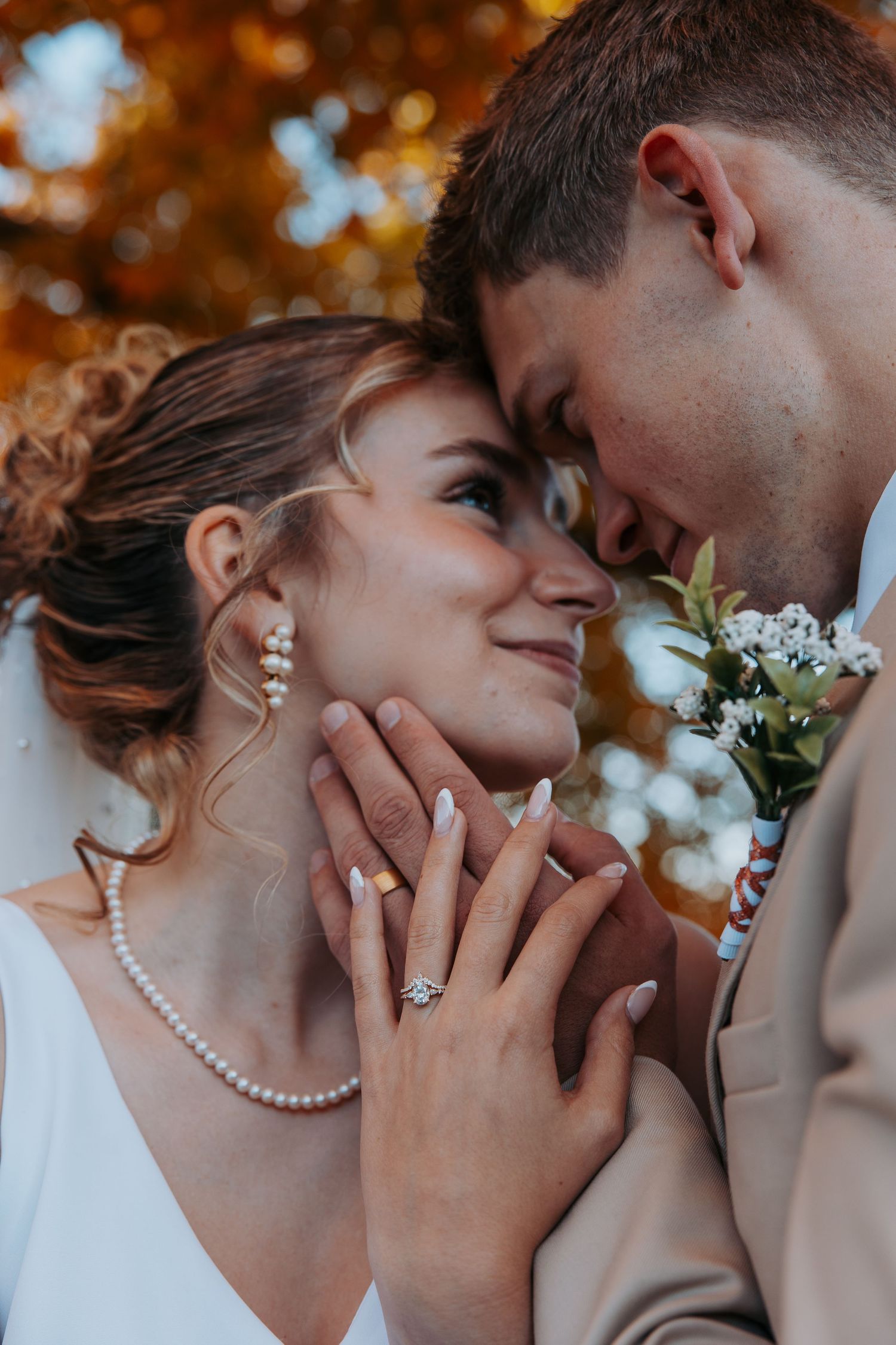 Romantic wedding couple sharing intimate close-up moments with autumn foliage in background.